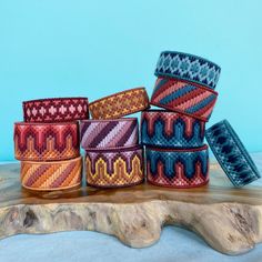 several different colored bracelets sitting on top of a piece of wood next to each other