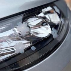 the front light of a car with flowers on it's headlight and chrome rims