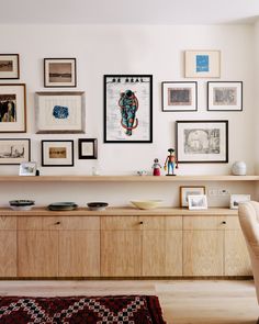 a living room filled with furniture and framed pictures on the wall above a wooden dresser