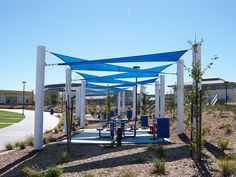 an outdoor play area with blue and white awnings