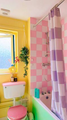 a pink and yellow bathroom with a toilet, bathtub, sink and shower curtain