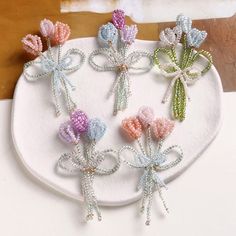 four different colored bows are on a white platter with beaded ribbon around them