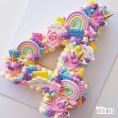 the letter e is made out of fondant and decorated with rainbows, unicorns, clouds, and flowers