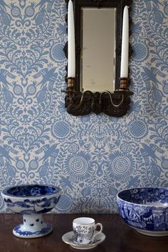 two blue and white bowls sitting on top of a wooden table next to a mirror