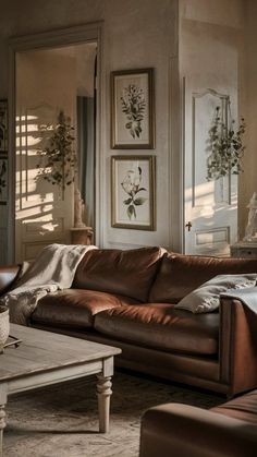 a living room with brown leather furniture and pictures on the wall above it's windows