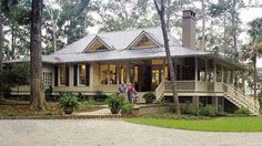 two people are standing in front of a house with porches and trees around it