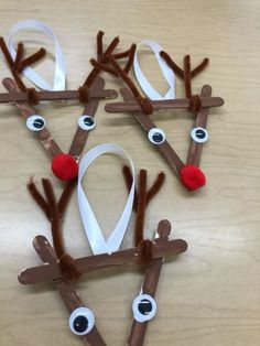 paper plate reindeers made out of sticks and white ribbon with red nose on them