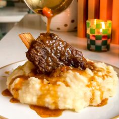 a white plate topped with mashed potatoes covered in gravy next to a glass of wine