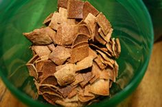 a green bowl filled with chips on top of a wooden table