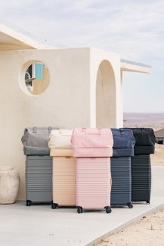 four suitcases lined up in front of a small white building with a round window