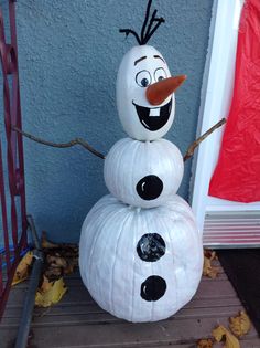 a snowman made out of pumpkins sitting in front of a door