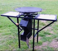 an outdoor bbq grill in the middle of a grassy field with two open drawers on it