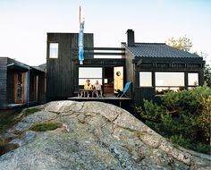 two people sitting at a table in front of a house on top of a rock