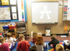 a group of children sitting on the floor in front of a projector screen