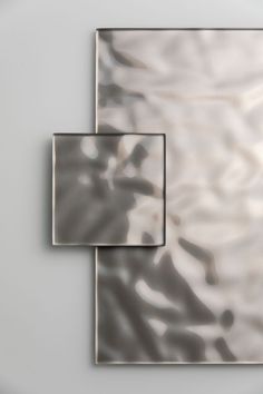 two square mirrors sitting next to each other on top of a white surface with light reflecting off them