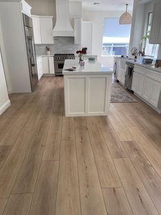 a kitchen with white cabinets and wood floors