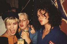 three young women are posing for the camera and one is holding a can of beer