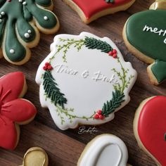 decorated christmas cookies and cookie cutters on a wooden table with merry lettering in the middle