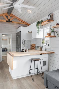 a kitchen with white walls and wood floors is pictured in this image, there are two stools at the island