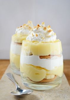 two glasses filled with dessert sitting on top of a table