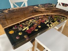 a wooden table with flowers painted on it and two white chairs in front of it