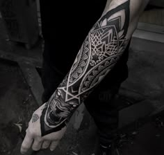 a man's arm with an intricate tattoo design on the left forearm and hand