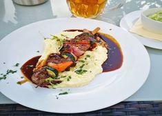 a white plate topped with mashed potatoes covered in meat and vegtables