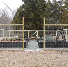 several cages are set up in the middle of a field with trees and bushes behind them