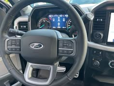 the interior of a vehicle with steering wheel controls and dashboard screen showing information on display