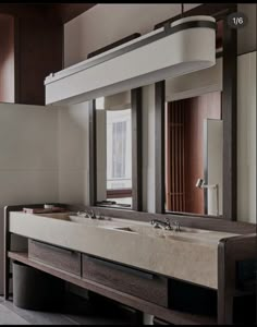 a bathroom with two sinks and large mirror above it's counter top, in front of a window