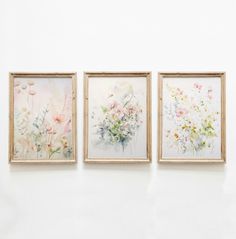 three floral paintings hang on the wall