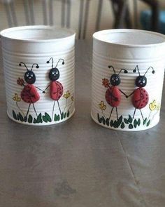 two white cups with ladybugs painted on them sitting on top of a table