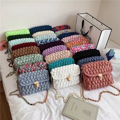 a bunch of purses that are sitting on a white table with a card holder