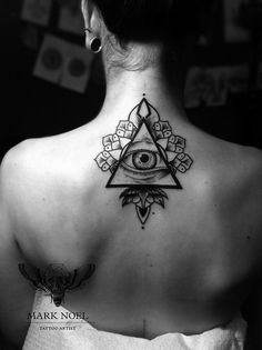 the back of a woman's neck with an all seeing eye tattoo