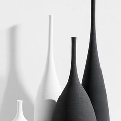 three black and white vases lined up against a wall