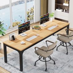 an office desk with two chairs and a computer monitor on the table in front of large windows