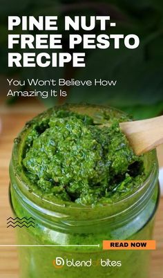 a jar filled with green pesto on top of a wooden table