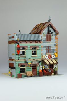 a building made out of legos with people standing outside and looking at the windows