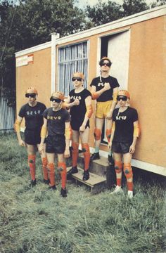 a group of young men standing next to each other in front of a small building