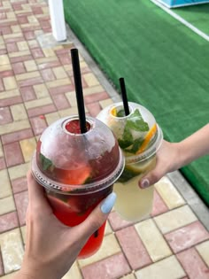 two people holding drinks in their hands on a tennis court with grass and artificial turf