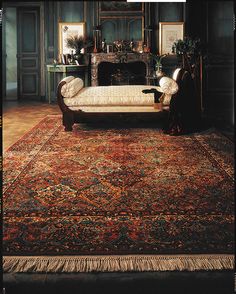 an old rug with a couch and fireplace in the middle, surrounded by other antique furniture