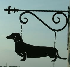 a metal sign with a dog hanging from it's side