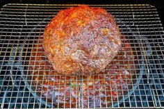 a large piece of meat sitting on top of a metal grill grate covered in ketchup