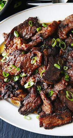 a white plate topped with meat and green onions