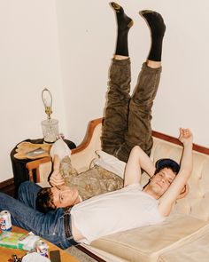 two people are laying on a couch with their feet up in the air and one person is wearing brown boots