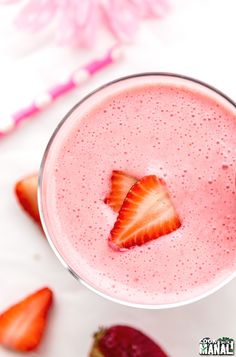 a strawberry smoothie in a glass with strawberries on the side