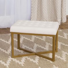 a white ottoman sitting on top of a rug in front of a window with curtains