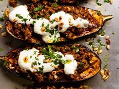 three stuffed eggplant halves topped with sour cream and nuts