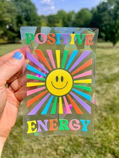 a person holding up a sticker with the words positive energy on it in front of a field