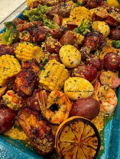 a blue tray filled with shrimp, corn and other foods on top of each other